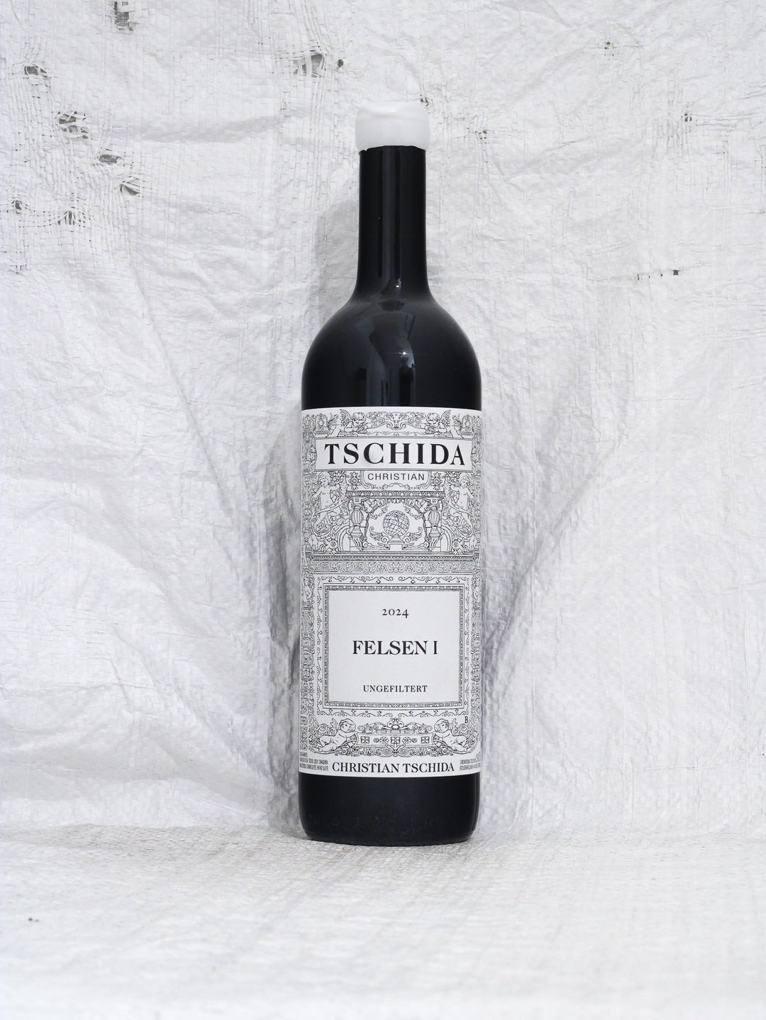 Vorderansicht der Flasche Christian Tschida Felsen I 2024, ein puristischer Syrah aus dem Burgenland. Minimal Intervention Naturwein mit dem charakteristischen künstlerischen Etikett.