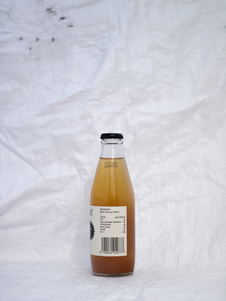 Seitenaischt einer Flasche Pona Bitterschön Bitter Lemon , eine naturtrübe Bio-Limonade mit Zitronensaft und echtem Chinin, unfiltriert und spritzig.